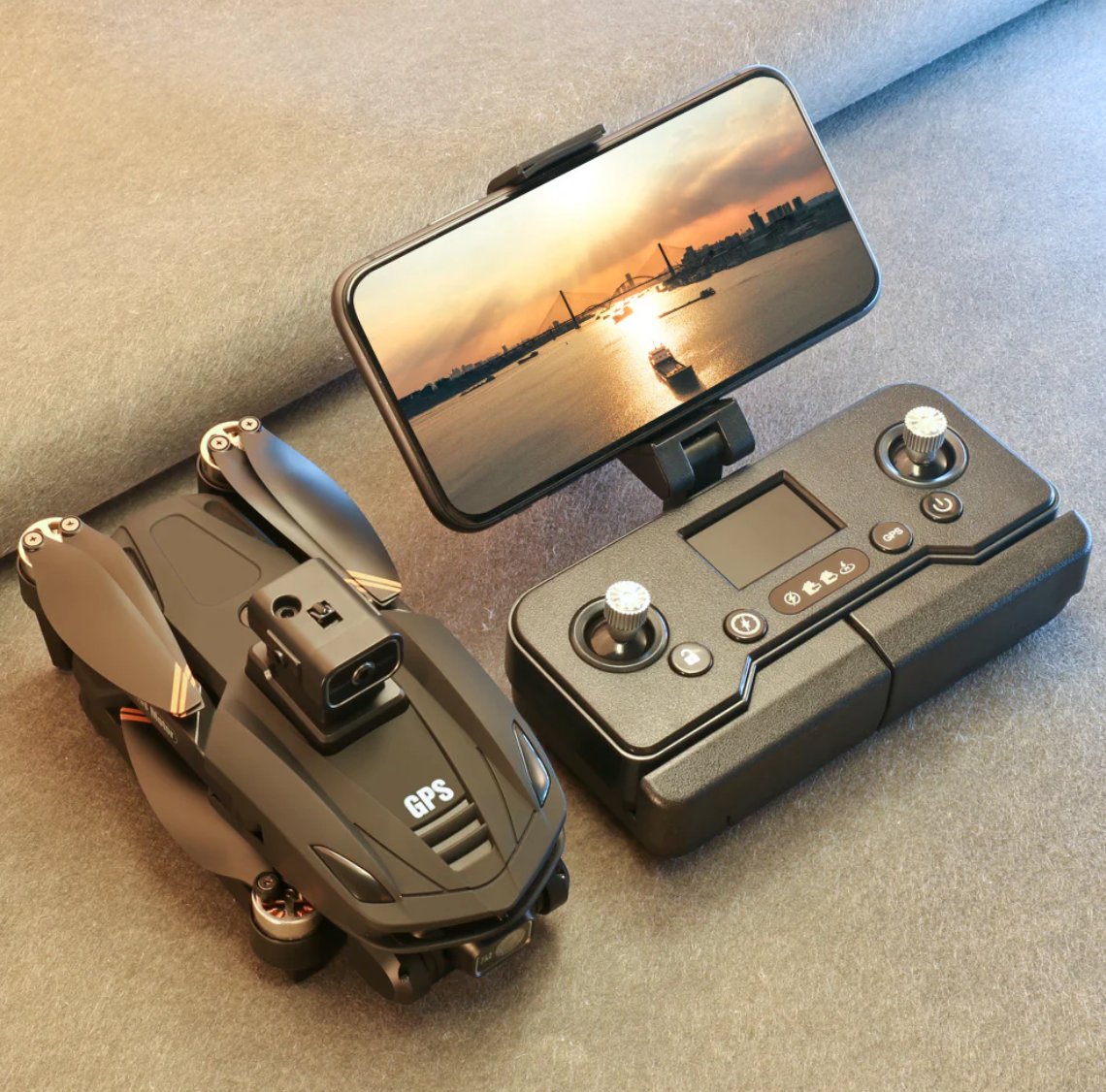 Black Caracen V168 Pro Max drone with remote control on a gray surface, displaying a sunset over water on a smartphone screen.