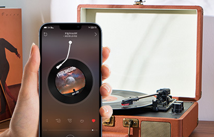 Person holding a smartphone with a music app displayed, next to a Auryvox Heritage VT-80 Portable Turntable