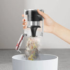 Hand using a Drexen Cordless Vacuum to sprinkle pepper into a white container on a neutral background