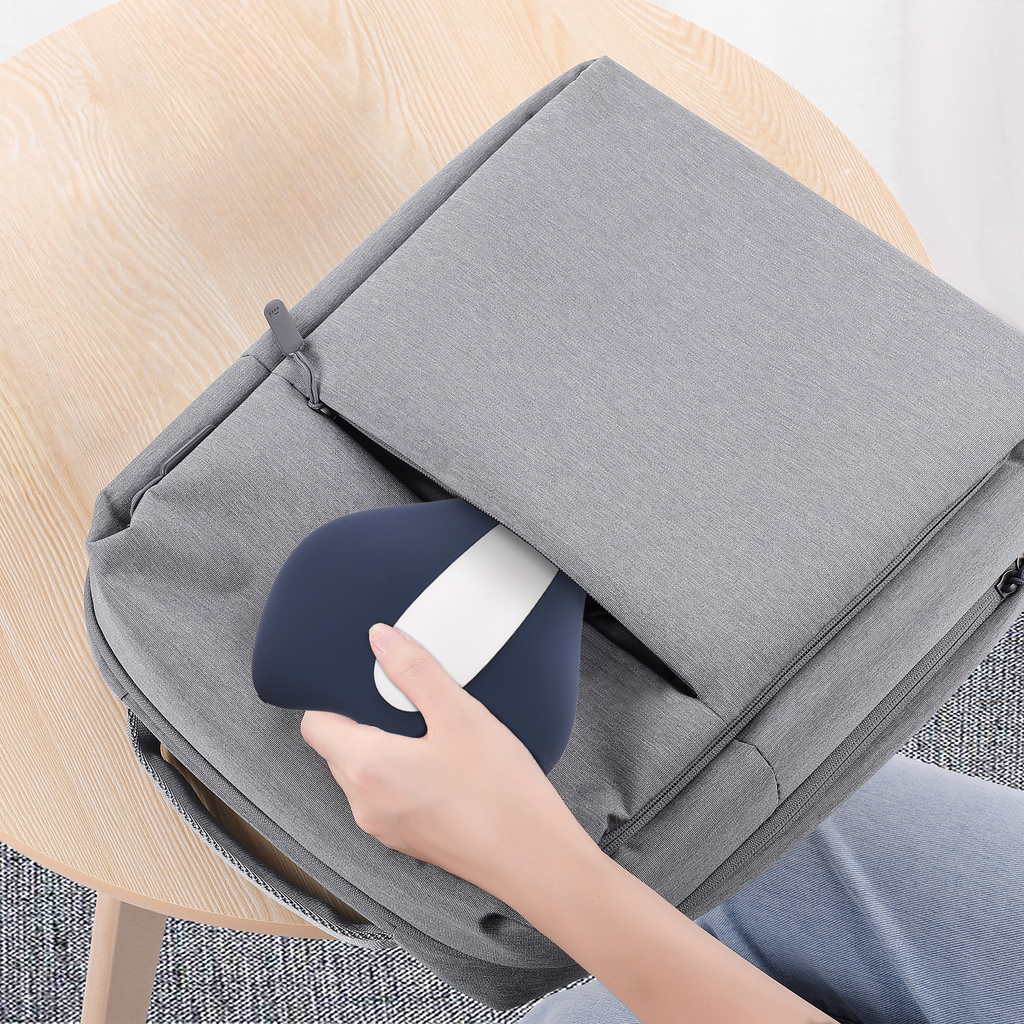 Person placing a blue and white Jovantic Pelvic Floor Trainer into a gray bag on a wooden chair.