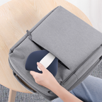 Person placing a blue and white Jovantic Pelvic Floor Trainer into a gray bag on a wooden chair.