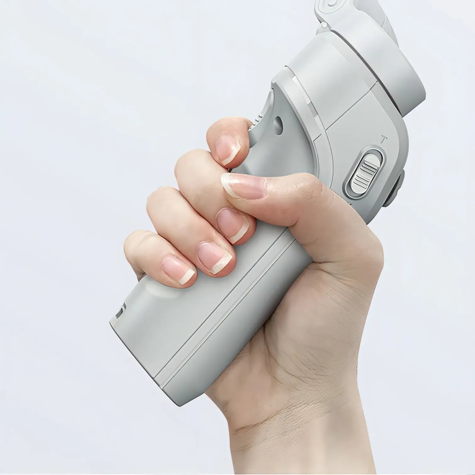 Hand holding a gray handheld Kozenix Gimbal against a light gray background