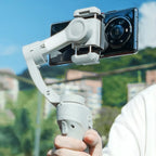 Hand holding a smartphone Kozenix Gimbal with a clear sky and blurred background