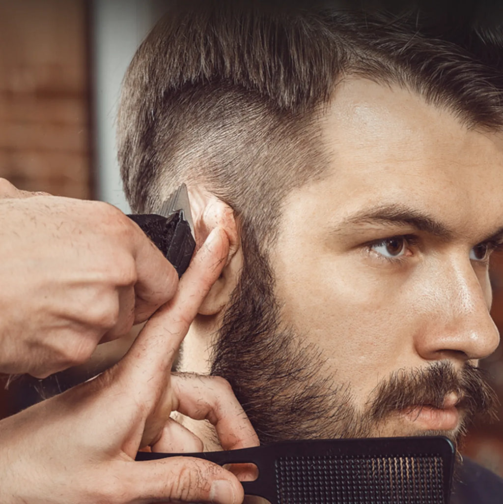 Barber trimming a customer's beard with a comb and Kozenix Hair Clipper in a close-up shot.