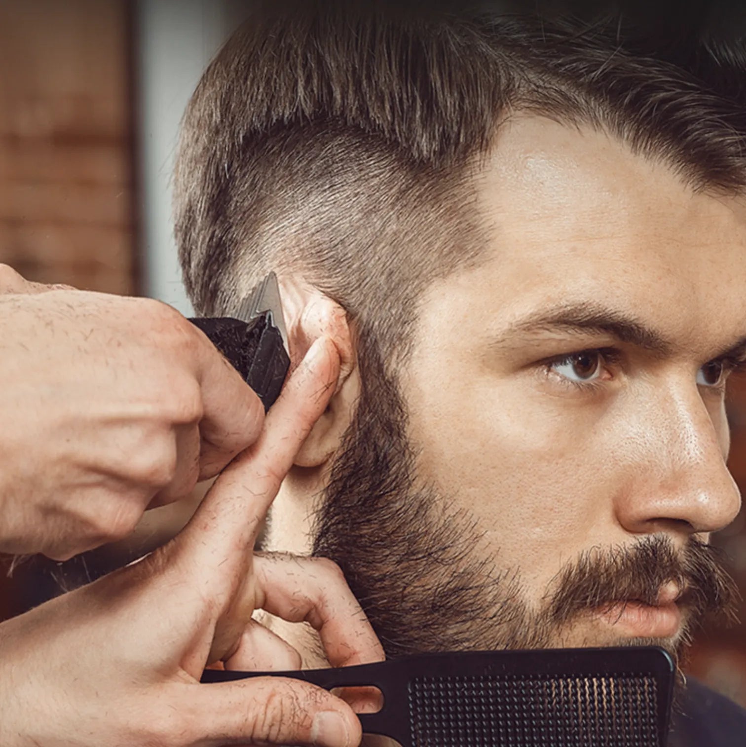 Barber trimming a customer's beard with a comb and Kozenix Hair Clipper in a close-up shot.