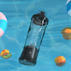 Black Kozenix Portable Blender on a blue underwater background with pool toys and fruit slices.