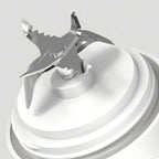 Close-up of a Kozenix Portable Blender blade on a swirl of white cream against a light gray background