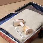 Meacode Steamer with cable on a folded blanket inside an open suitcase.