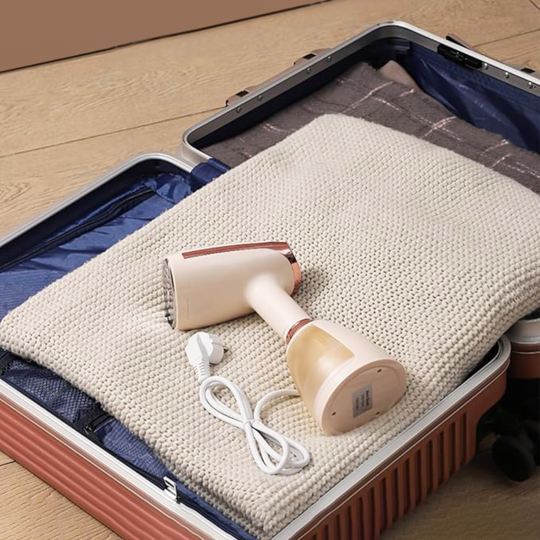 Meacode Steamer with cable on a folded blanket inside an open suitcase.