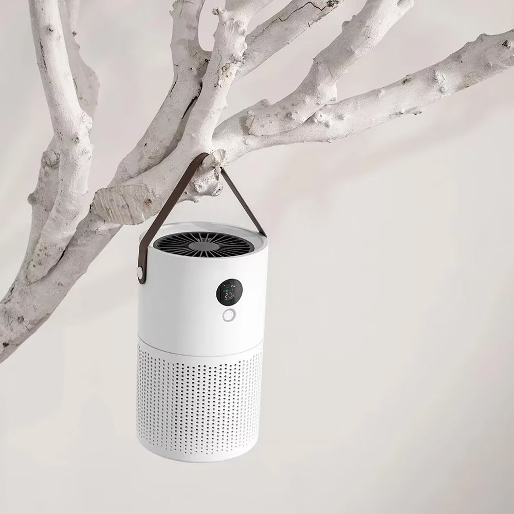 A white cylindrical portable SkyPhis Air Purifier with a dark brown hanging strap, suspended from a white tree branch against a light off-white background.