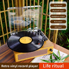 Retro VinyyLux Record Player with a vinyl record on a wooden surface, surrounded by greenery.