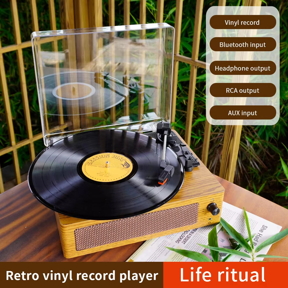 Retro vinyl Klarity Record Player with a vinyl record on a wooden surface, surrounded by greenery.